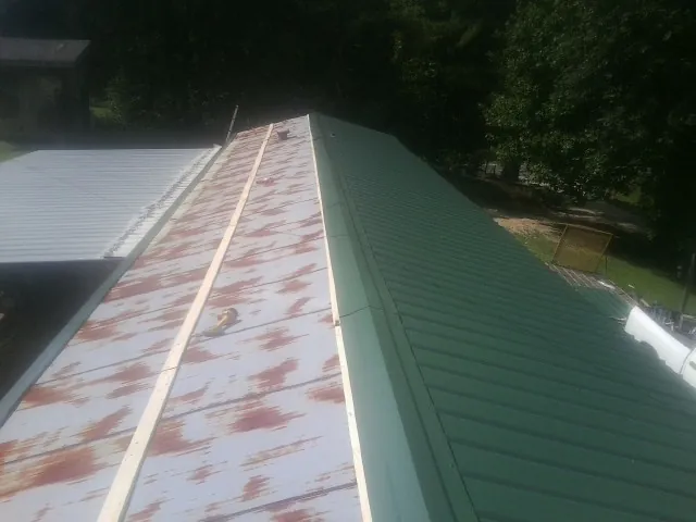 Old rusted panels beside newly installed green metal roofing — Wind Damage Roof Repair by Roofing Brothers in Plattsmouth