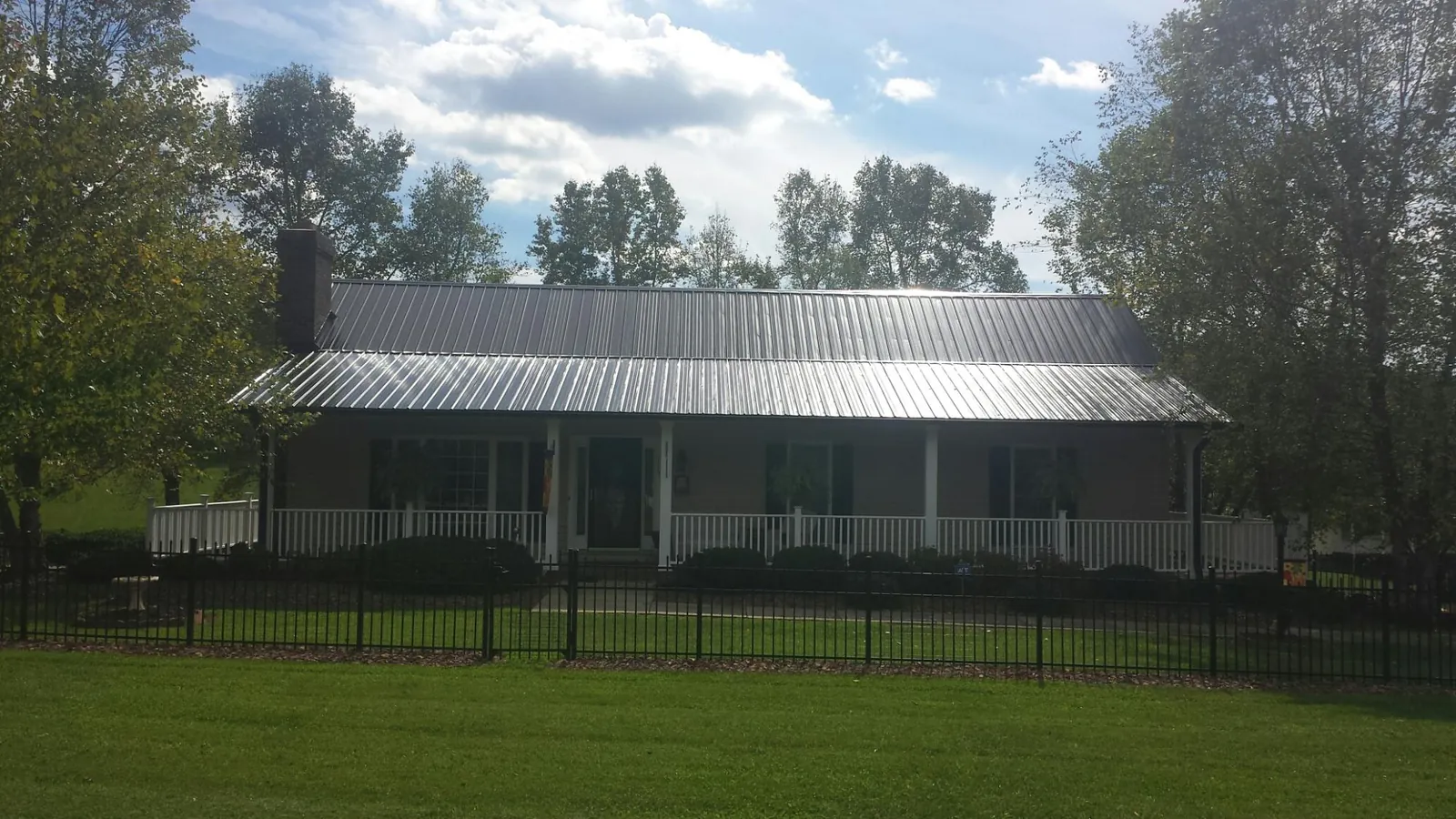 Gray metal roof on a brick ranch with a full width front porch — Gutter Guard Installation work by our crew in Plattsmouth