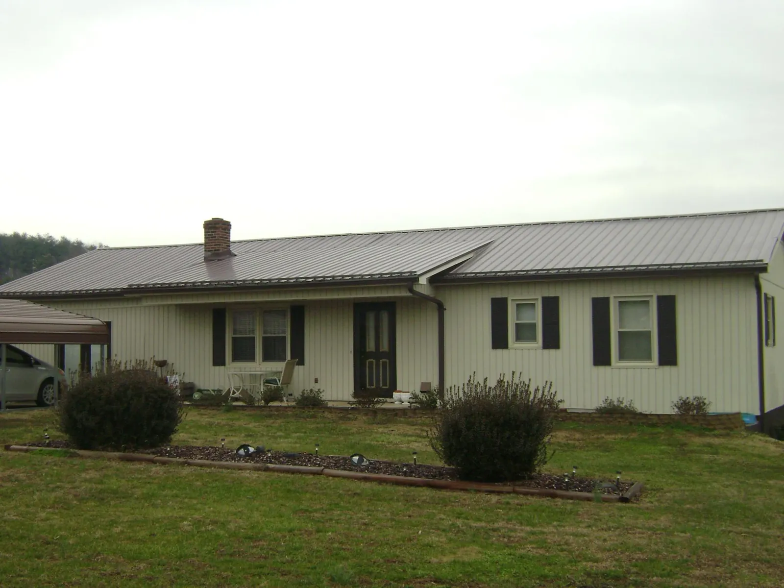 Brown metal roof on a cream sided ranch home with a brick chimney in Plattsmouth