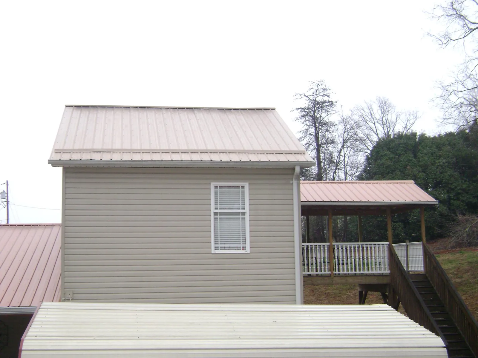 Tan metal roofs on a two story addition and attached porch, from a Roof Replacement job in Plattsmouth
