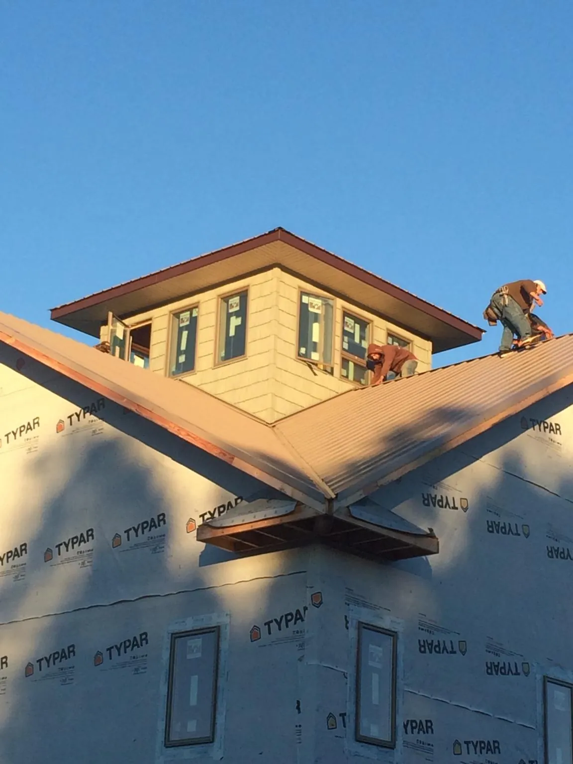 Roofers working around a rooftop cupola on a new metal roof at sunset — Roof Waterproofing in Plattsmouth by Roofing Brothers